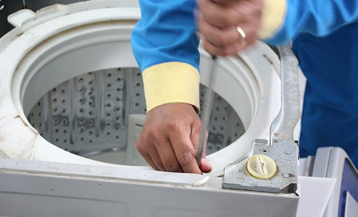Bạn dùng tua-vít để tháo ốc vít cố định lồng giặt, rồi tiến hành tháo miếng ốp nhựa cố định lồng giặt