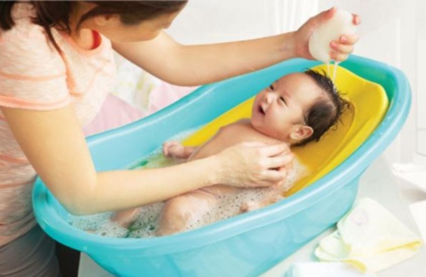 Dùng khăn xô thấm nước lau nhẹ lên người bé