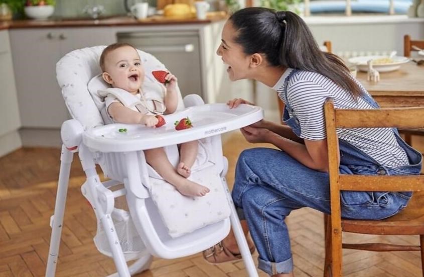 Cho bé ngồi vào ghế ăn dặm, thắt dây an toàn và kiểm tra độ chắc chắn của ghế