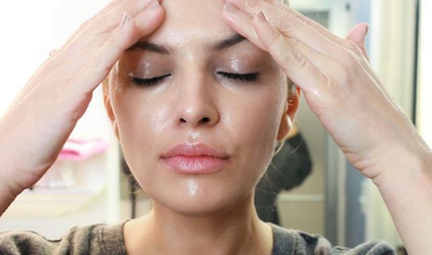 Thoa dầu tẩy trang lên mặt