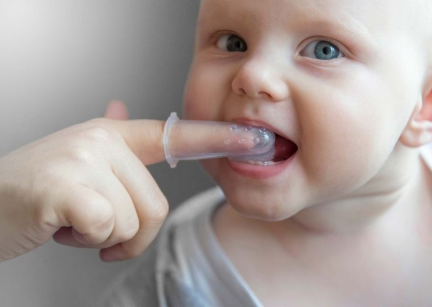 Cha mẹ xoa vào vùng nướu đang bị đau của trẻ. Nguồn từ squarepaces