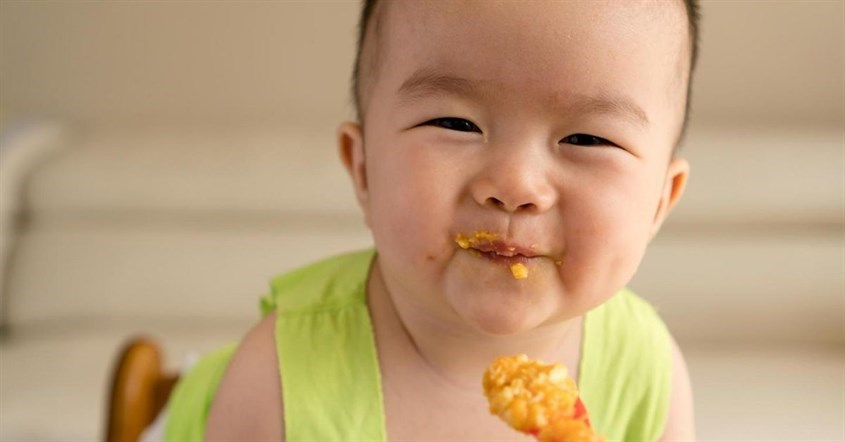 Khi con đã cứng cổ và có thể ngồi độc lập, ba mẹ có thể mời con những bữa ăn dặm đầu tiên. Nguồn ảnh: iStock