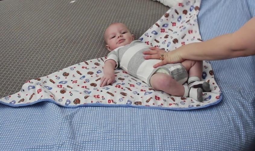 Điều chỉnh tư thế và đặt bé nằm cố định trên tã