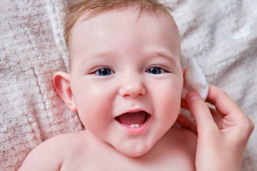 Làm sạch tai cho trẻ sơ sinh bằng khăn mềm ngâm nước ấm - Nguồn: istockhoto