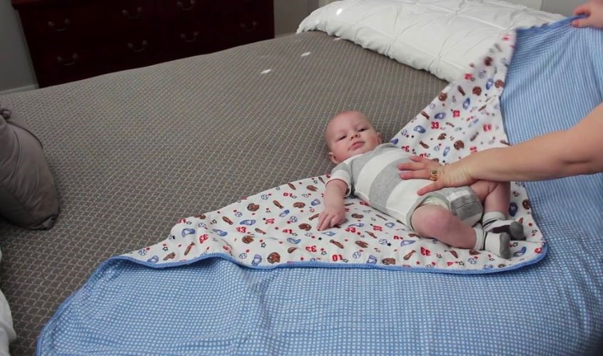 Đặt phần vai của bé ngang với mép trên của tã