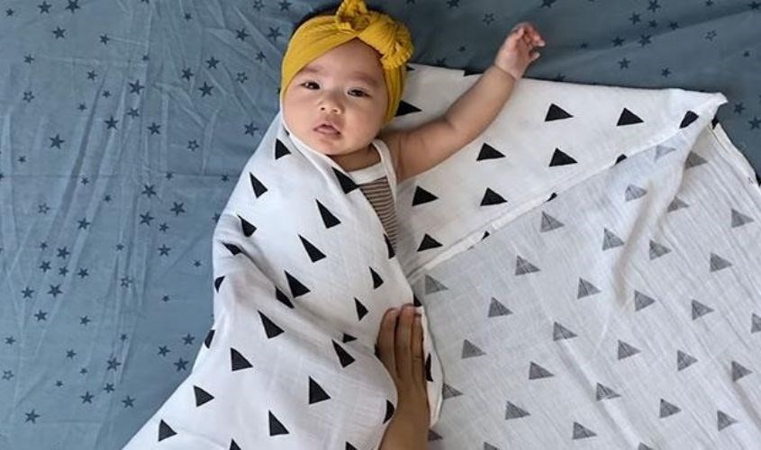 Trải khăn theo hình thoi trên mặt phẳng rộng rồi đặt bé vào giữa