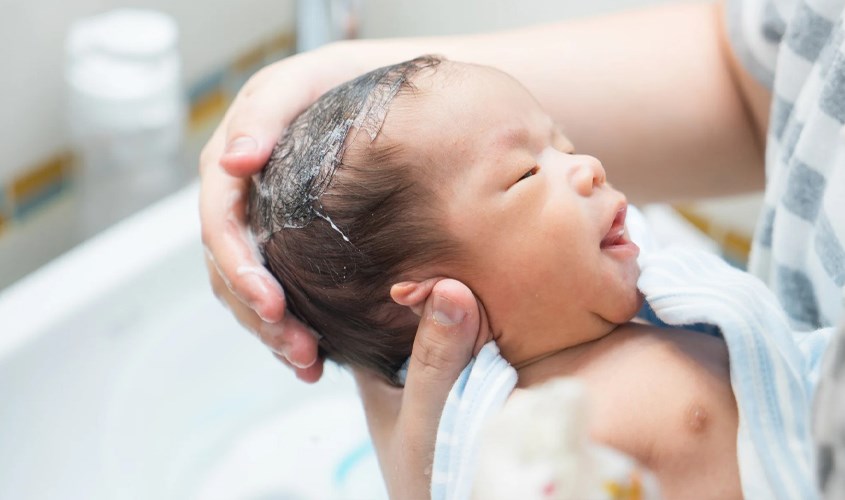 Dùng tay không xoa dầu gội dành cho bé lên da đầu của trẻ