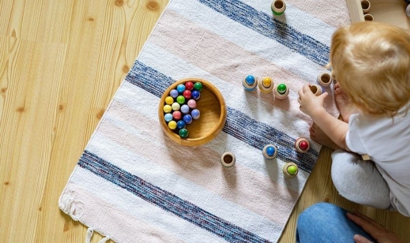 Thả đồ vật vào xô giúp bé phát triển được các kỹ năng vận động và ngôn ngữ