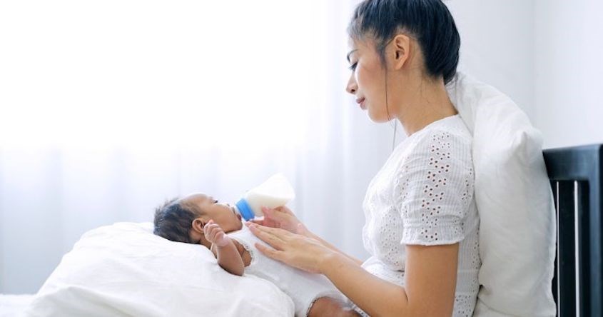 Tựa lưng của bé lên đùi của mẹ để cho bé bú