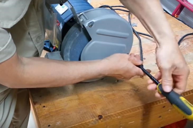 Dùng vít 4 chấu để tháo bao che hai bên đá mài