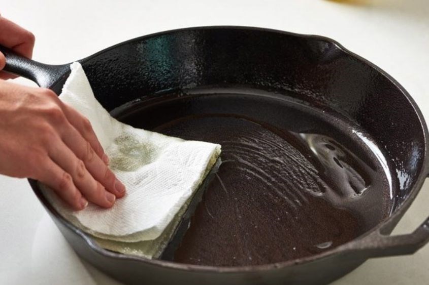 Dùng khăn giấy làm sạch dầu mỡ dính trong nồi, chảo
