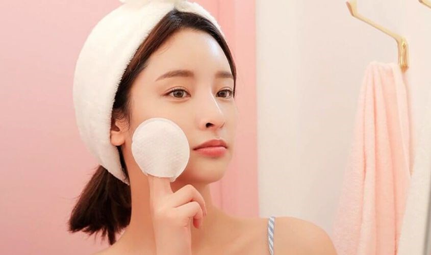 Dùng bông để lau bớt các dưỡng chất thừa và massage mặt
