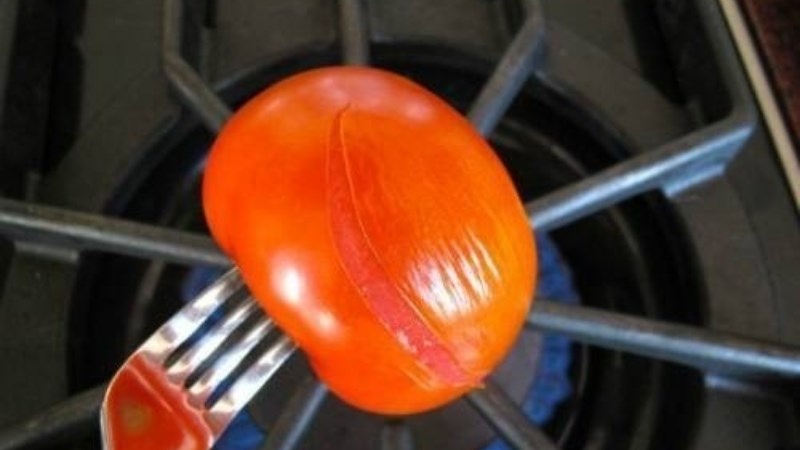 Dùng nĩa xiên vào cà chua và hơ lên lửa