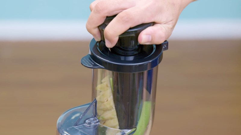 D&ugrave;ng thanh nhấn của m&aacute;y &eacute;p chậm Crystal GS-137L để đảy tr&aacute;i c&acirc;y xuống