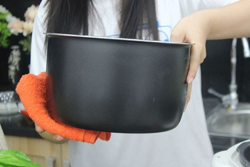 Lau kh&ocirc; mặt ngo&agrave;i của nồi con trước khi đặt v&agrave;o nồi cơm điện