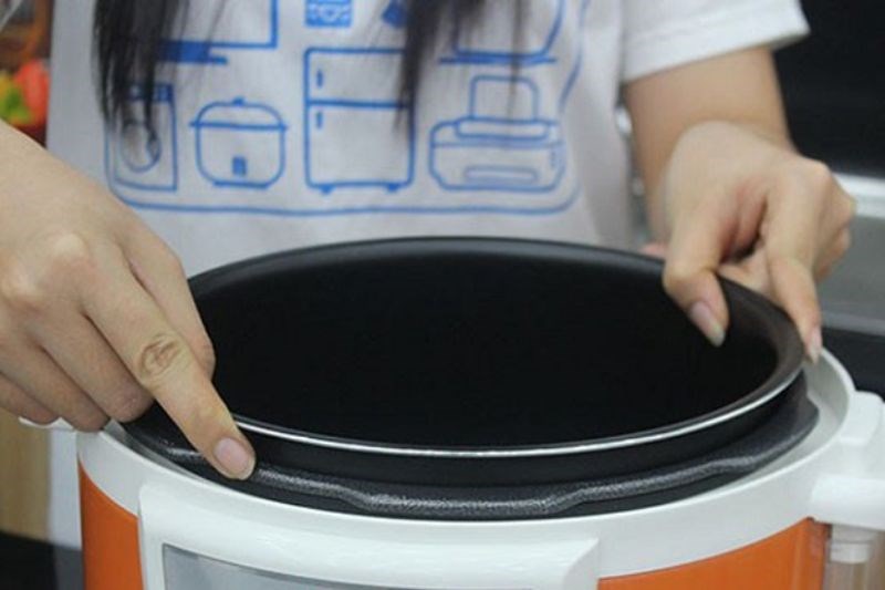 D&ugrave;ng 2 tay đặt nồi con v&agrave;o nồi cơm điện