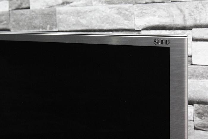 Cạnh phải phía trên của tivi nổi bật với logo SUHD được cố định trực tiếp vào khung viền