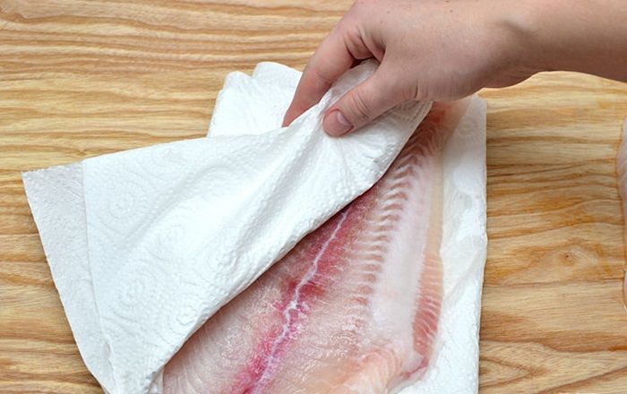 Làm sạch cá với một chiếc khăn giấy, bạn đặt miếng cá lên khăn giấy, dùng tay ấn mạnh để khăn giấy hút hết nước dư thừa trên miếng cá. Với những miếng cá đông lạnh và mới được rã đông bằng lò vi sóng, bạn càng nên sử dụng khăn giấy để hút nước thì khi nướng, cá sẽ ngon hơn.