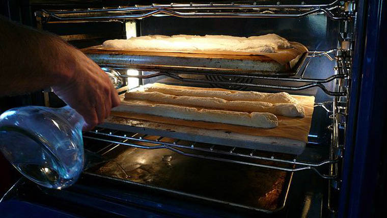 Đổ nước nóng xuống khay nướng dưới cùng để thêm độ ẩm cho bánh mì
