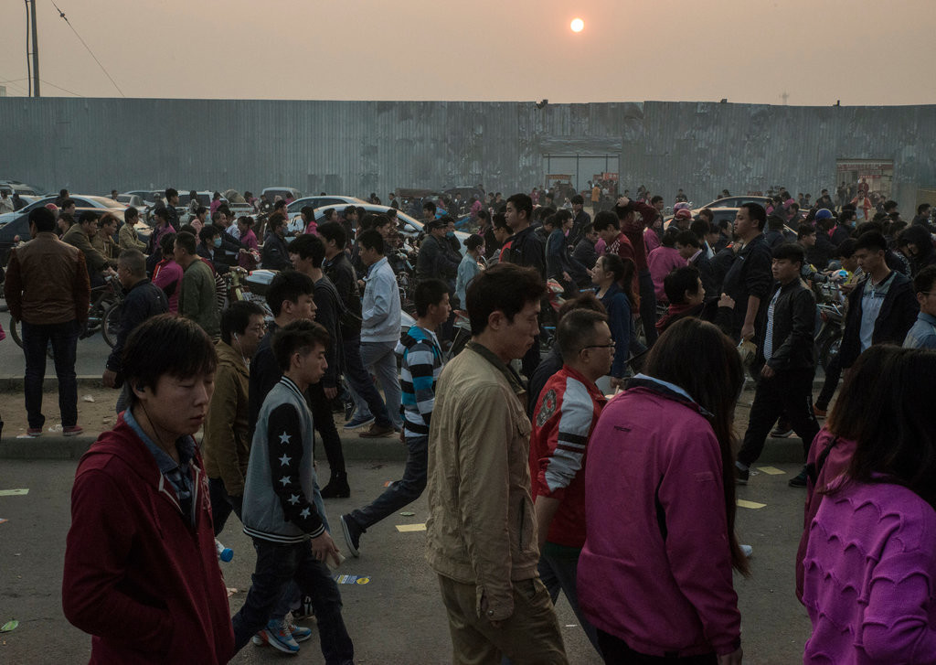 Công nhân nhà máy Foxconn tại Trịnh Châu rời nơi làm việc sau một ca đêm, những người còn lại bắt đầu ca làm việc ban ngày của mình. Ảnh: New York Times