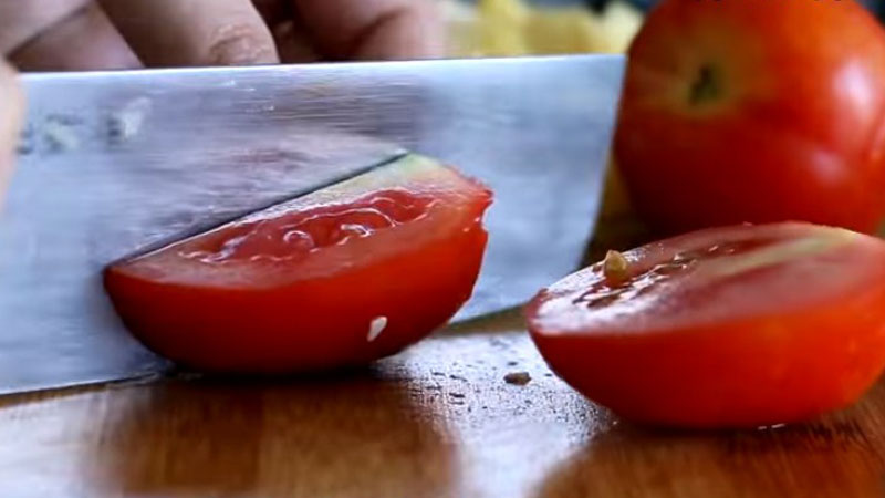 Cà chua rửa sạch, cắt đôi ra rồi bỏ phần hạt bên trong, sau đó cắt thành từng miếng vừa ăn.