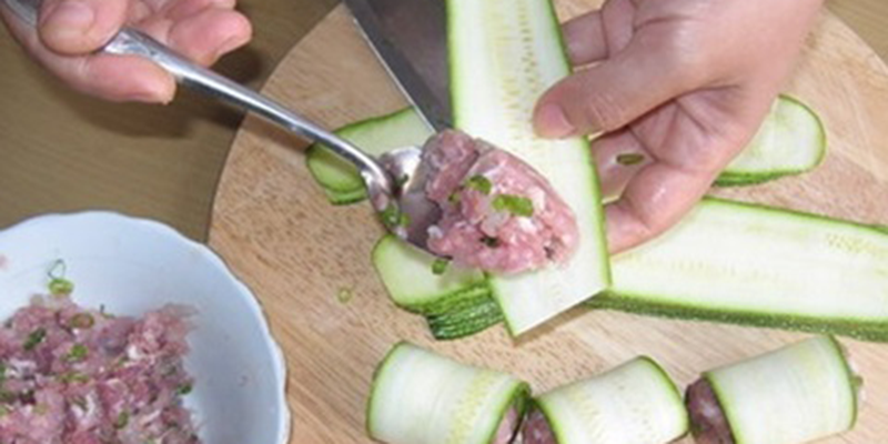 Dùng tay lấy một lượng chả cá nhỏ cỡ bằng đầu ngón tay. Để vào giữa miếng bí ngòi, cho thêm 1 vài sợi cà rốt lên trên và cuồn lại.