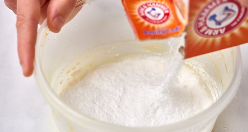 Rắc baking soda vào hộp nhựa để trong vài phút rồi dùng khăn vải hay miếng bọt biển chà nhẹ nhàng