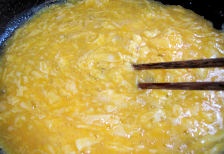 Bước 2: Cháo chín bạn mở nắp cho trứng gà tươi vào nồi cháo và khuấy để trứng tan ra và chín đều.