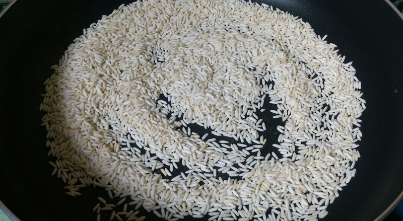 Gạo vo sạch, để ra rổ cho ráo nước. Tiếp theo bắt chảo lên bếp thêm vào 1 thìa hành đã phi và gạo vào rang chung. Rang đến khi hạt gạo khô thì tắt bếp.