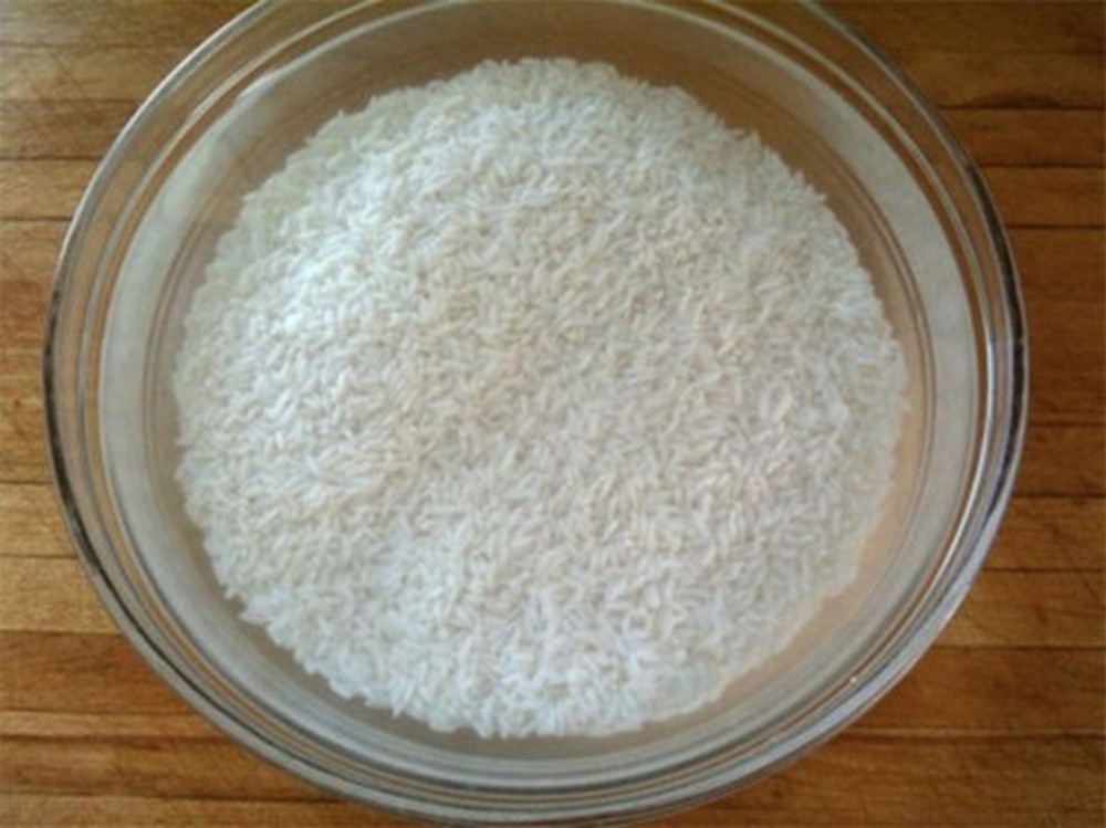 Gạo tẻ vo sạch, ngâm nước 30-45 phút để gạo nở mềm. Sau khi ngâm chúng ta để ráo gạo rồi dùng chày giã vỡ hạt gạo để khi nấu gạo sẽ nhanh mềm, nở đều.