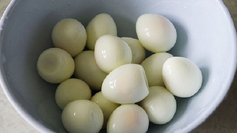 Trứng cút rửa sạch, sau đó đem đi luộc chín, rồi để nguội, lột bỏ vỏ, cho vào tô.