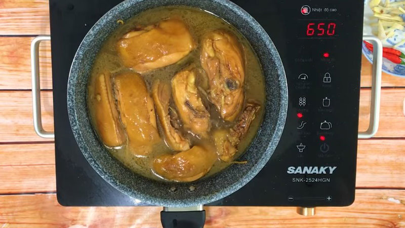 Nấu trong 2 phút cho thịt gà thấm gia vị, rồi cho nước lọc vào, hạ nhỏ lửa và kho thịt gà trong 20 phút.