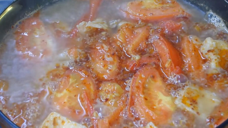 Cho hết phần cà chua đã xào cùng với sa tế khô, mắm tôm, hạt nêm, đường và tàu hủ vào, tiếp tục nấu đến khi nước sôi lên lại thì tắt bếp.