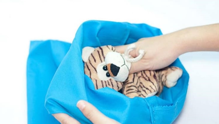 Putting the teddy bear in a laundry bag