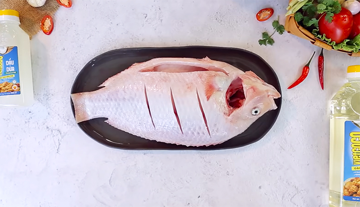Mổ bụng cá, sau đó sơ chế cá sạch, không tanh, và dùng dao khía 3 đường lên thân cá