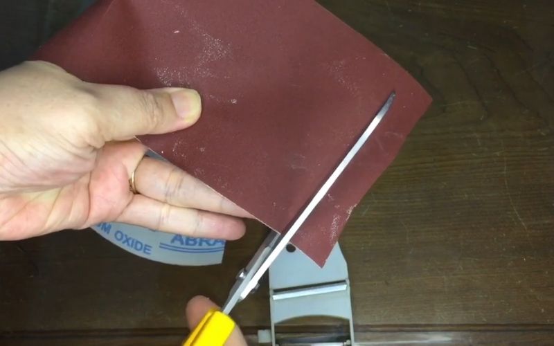 Bước 1: Bạn dùng chiếc kéo cắt một miếng giấy nhám hình chữ nhật ra.