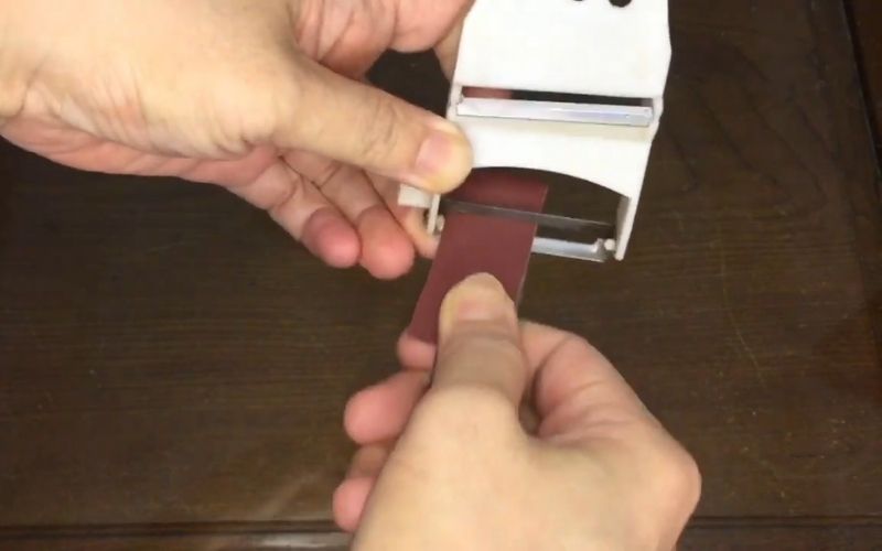 Bước 3: Sau đó, bạn cho miếng giấy nhám cùng lưỡi cưa ở bước trên vào giữa phần của dao nạo và bắt đầu đẩy đi đẩy lại như thao tác mài dao vậy.