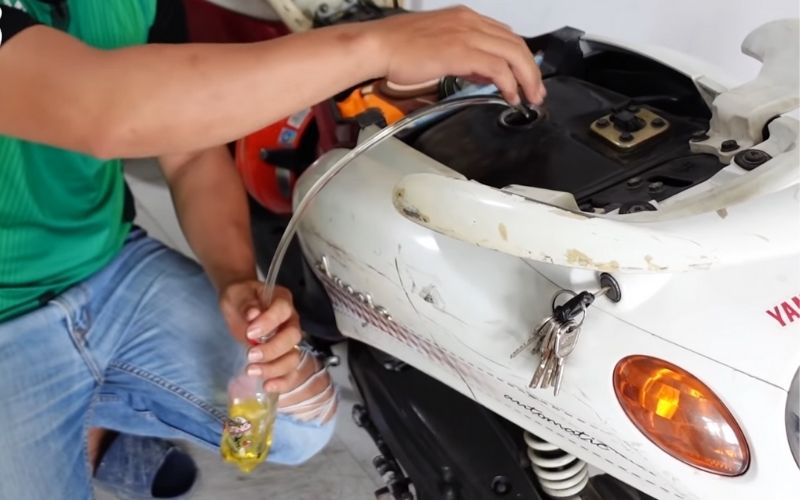 Bước 3: Bạn chờ đến khi nào xăng chảy ra chai tới một mức vừa đủ thì đem chai xăng này đổ vào bình xăng của chiếc xe máy đang hết xăng khác là được.