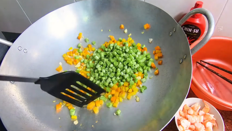 Cho cà rốt và đậu que vào chảo, xào đều trong 4 phút.