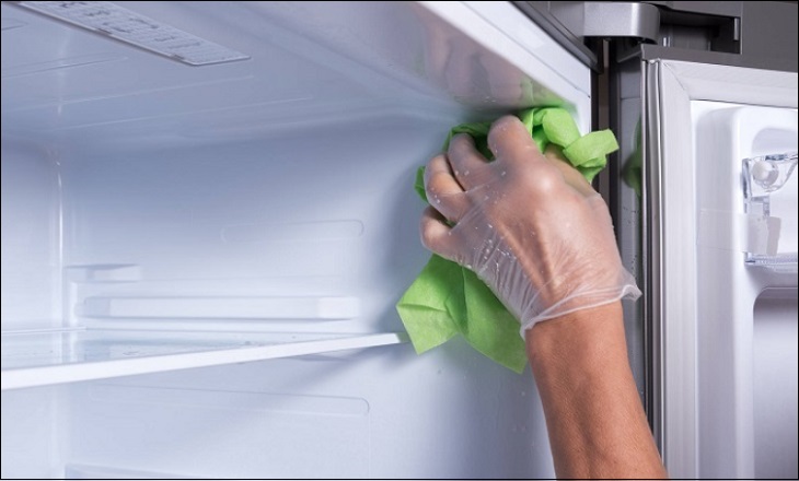 Using a cloth to wipe the interior of the mini refrigerator