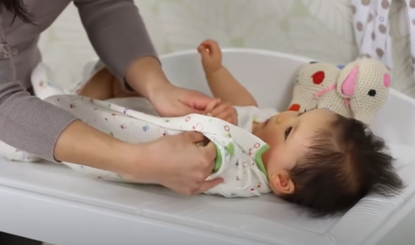  Luồn tay bé lần lượt vào tay áo.