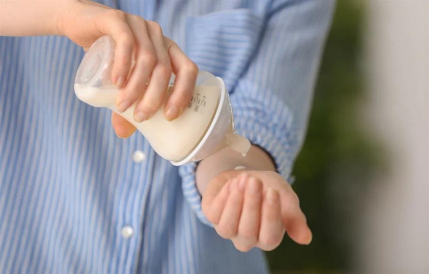 Nhỏ sữa ra tay để kiểm tra nhiệt độ sữa trước khi cho bé uống